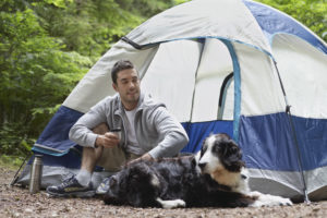 Man with dog sitting by tent